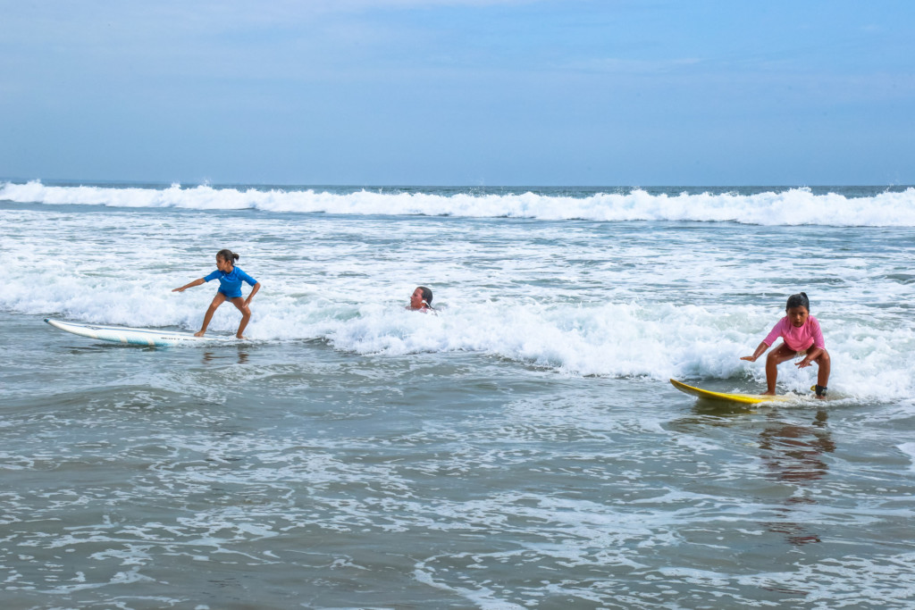 Two young determined Ecuadorian girls shredding in the surf