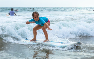 Close up of young Ecuadorian girl riding a wave into shore